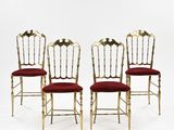 four gold chairs with red upholstered cushions and a white background