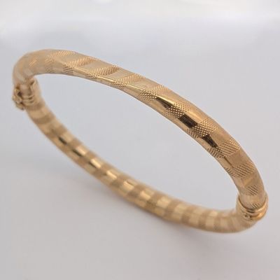 gros plan d'un bracelet en or sur une surface blanche