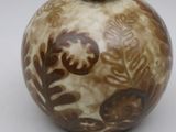 un vase brun et blanc posé sur une surface blanche