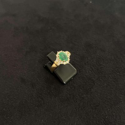 une image représentant une bague ornée d'une pierre verte sur un fond noir