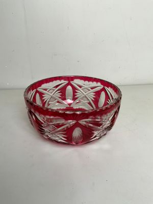 un saladier en verre rouge posé sur une table blanche