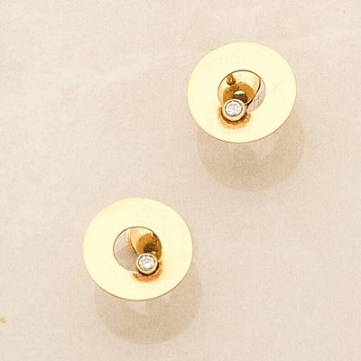 two pairs of gold and diamond stud earrings sitting on a white surface