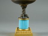 a gold and blue vase with a bird on top of it