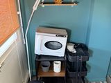a small kitchen with a microwave and a stool in the corner