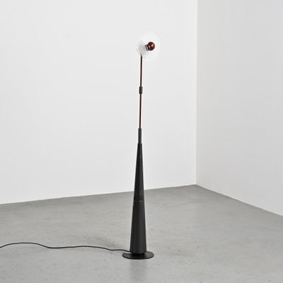 une image représentant une lampe posée sur un pied au milieu d'une pièce