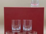 four shot glasses and a box of water sit on a table