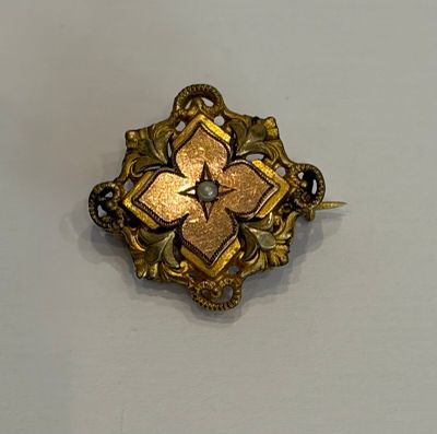 une broche en or ornée d'une fleur sur un fond blanc