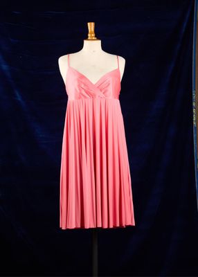 une robe rose posée sur un mannequin, devant un fond bleu