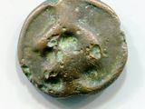 une vieille pièce de monnaie sur laquelle est représenté un visage, posée sur une surface blanche