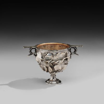 an antique silver cup with two handles and a flower decoration
