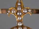 a close up of a ring with pearls and a cross on it