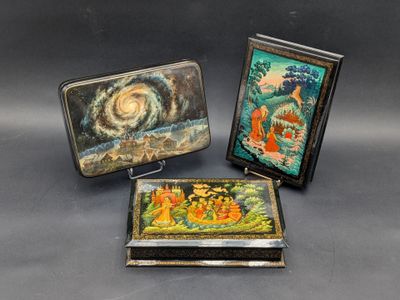three small metal boxes with paintings on them sitting on a table