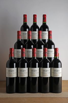 des bouteilles de vin rouge sont posées sur une table en bois devant un mur blanc
