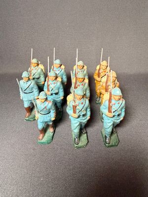 Plusieurs figurines représentant des hommes en uniforme bleu sont alignées sur une surface grise
