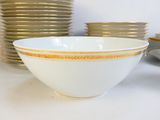 a white bowl with a yellow stripe on it next to a stack of plates