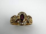 a close up of a gold ring with a ruby stone and diamonds