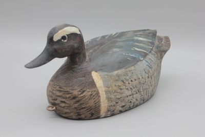 un canard en bois posé sur une surface blanche