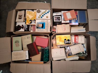 de nombreux livres dans une boîte en carton posée sur le sol