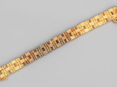 Gros plan sur un bracelet en or orné d'une croix