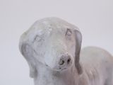 a small statue of a dog sitting on a white surface