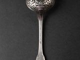 silver spoon on a black background with a pattern on the handle