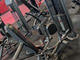 rows of machines in a gym with red seats and black flooring