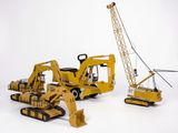 trois engins de chantier miniatures et une grue sur fond blanc