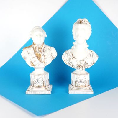 une paire de bustes en marbre blanc représentant un homme et une femme, sur fond bleu