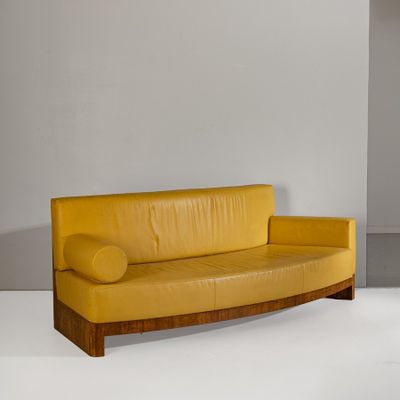 a yellow leather couch sitting in a white room