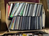 une boîte remplie de CD et des CD posés par terre