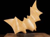 a close up of a sculpture of a bat on a wooden surface