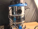 un aspirateur argenté et bleu posé sur une table en bois