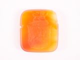 un savon orange posé sur une surface blanche