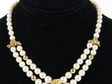 a necklace with pearls and gold beads on a black mannequin