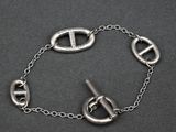 bracelet en argent muni d'un fermoir, suspendu à une chaîne sur un fond noir