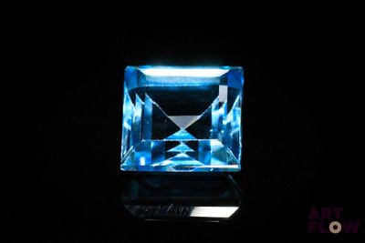 an aquamarine blue topazte gems on a black surface