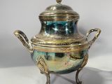 silver plated teapot on stand on white surface with light gray background