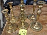 Plusieurs bougies en laiton sont posées sur une table en bois à côté d'un mannequin