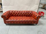 an image of a red leather couch sitting on top of a hard wood floor