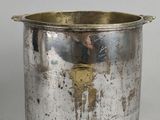 a silver pot with a gold handle on a table