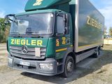 un camion vert garé sur la terre battue