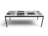 La table est composée de carreaux noirs et blancs, avec un cadre en métal noir.