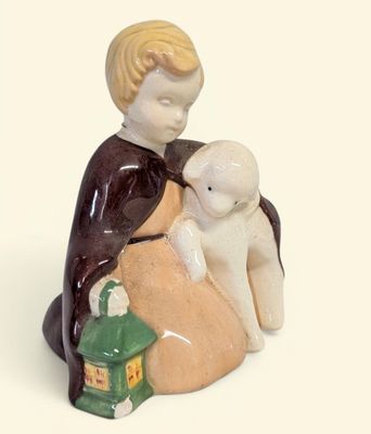 une figurine représentant un garçon assis sur un rocher avec un chien