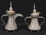 pair of antique silver plated teapots on stand on black background