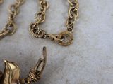 a gold necklace with a bird on it on a marble surface