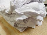 a stack of folded white shirts on a wooden table