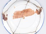 a white plate with a blue border and a brown plate with a brown piece of paper on it