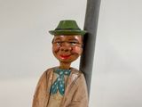 a wooden statue of a man with a green hat