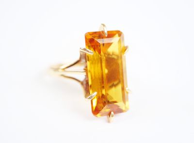 a close up of a ring with an orange stone in it