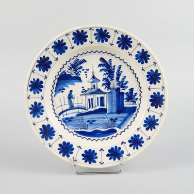 une image représentant une assiette bleue et blanche sur laquelle figure un homme sur un pont